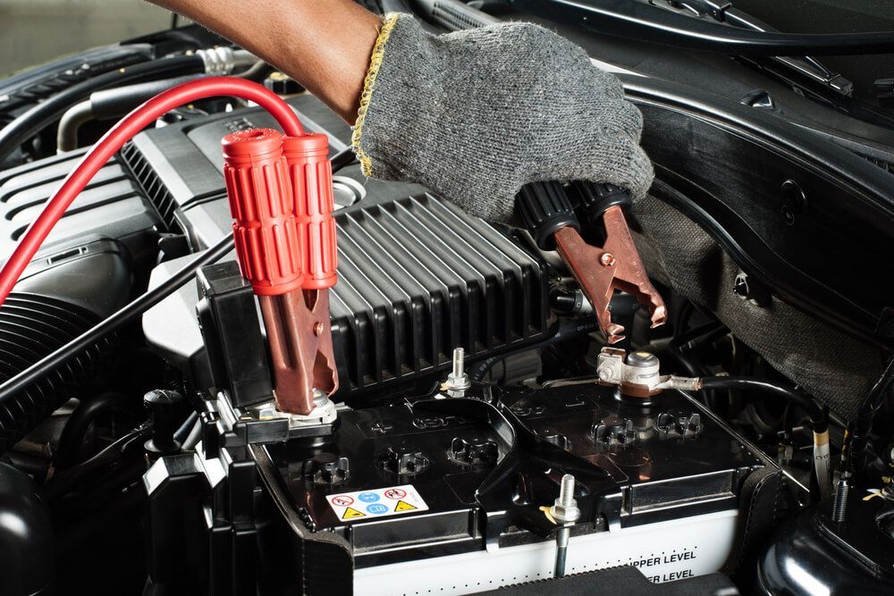 A Person Is Charging A Car Battery With Jumper Cables — Coast 2 Coast Batteries in Terrigal, NSW