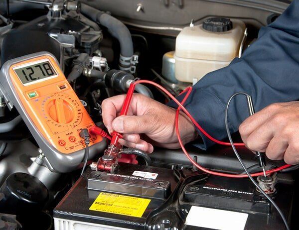 A Man Is Using A Multimeter To Test A Car Battery — Coast 2 Coast Batteries in Erina, NSW