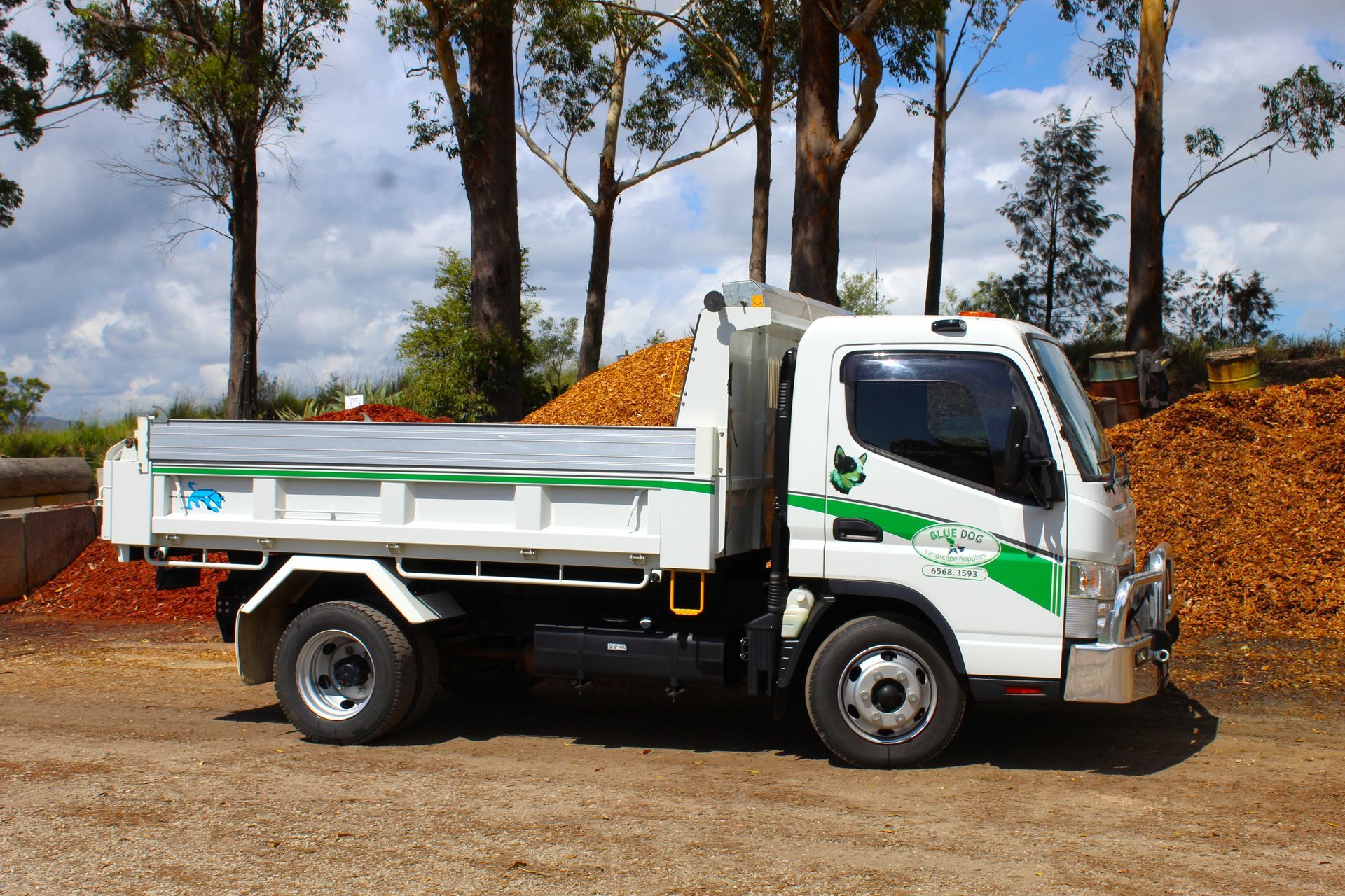 A white dump truck is parked in front of a pile of wood chips — Blue Dog Landscape Supplies In Newee Creek, NSW