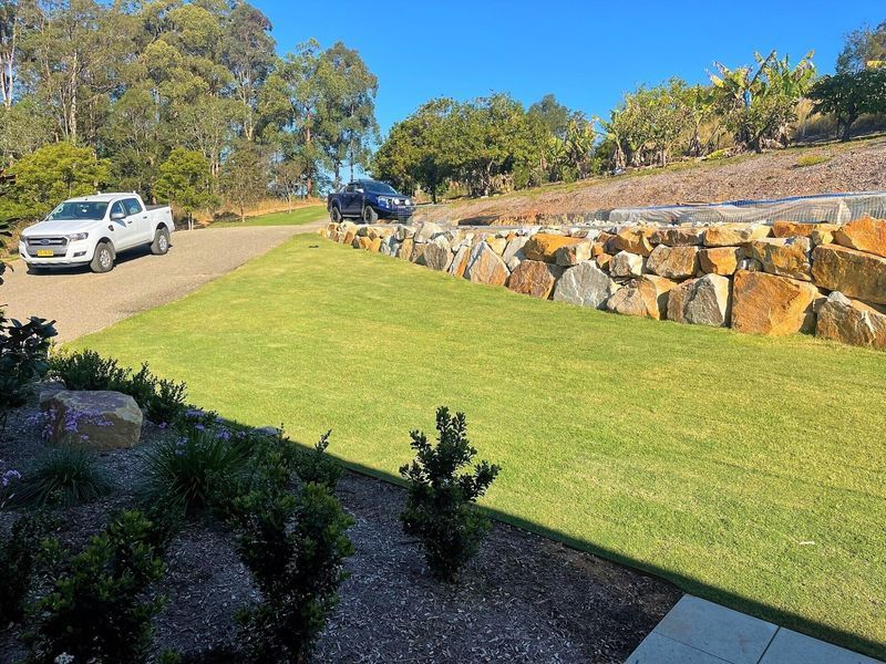 A White Truck Is Parked In The Grass Next To A Stone Wall — Blue Dog Landscape Supplies In Newee Creek, NSW