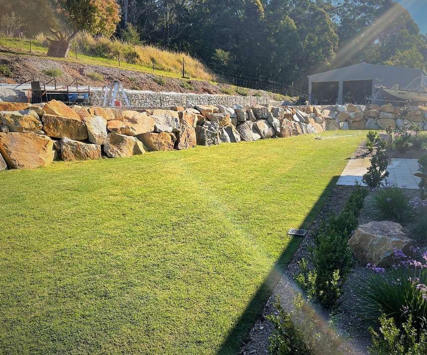 A Lush Green Lawn With A Stone Wall In The Background — Blue Dog Landscape Supplies In Newee Creek, NSW