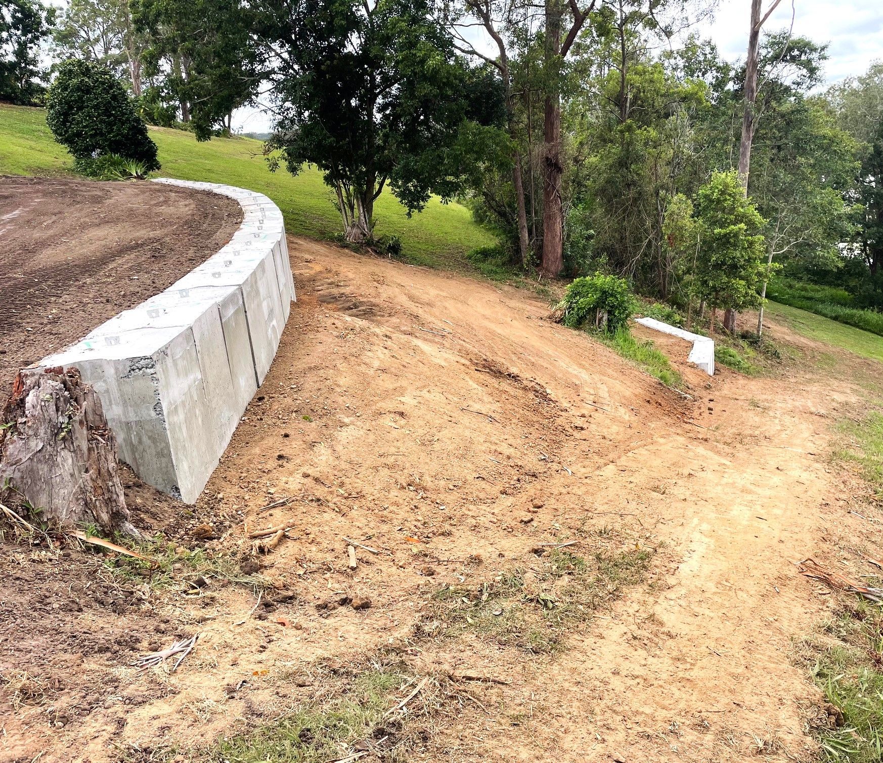 A dirt road with a concrete wall on the side of it — Blue Dog Landscape Supplies In Newee Creek, NSW