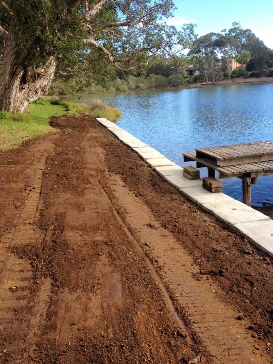 A Dirt Road Leading To A Lake With A Dock In The Background — Blue Dog Landscape Supplies In Newee Creek, NSW