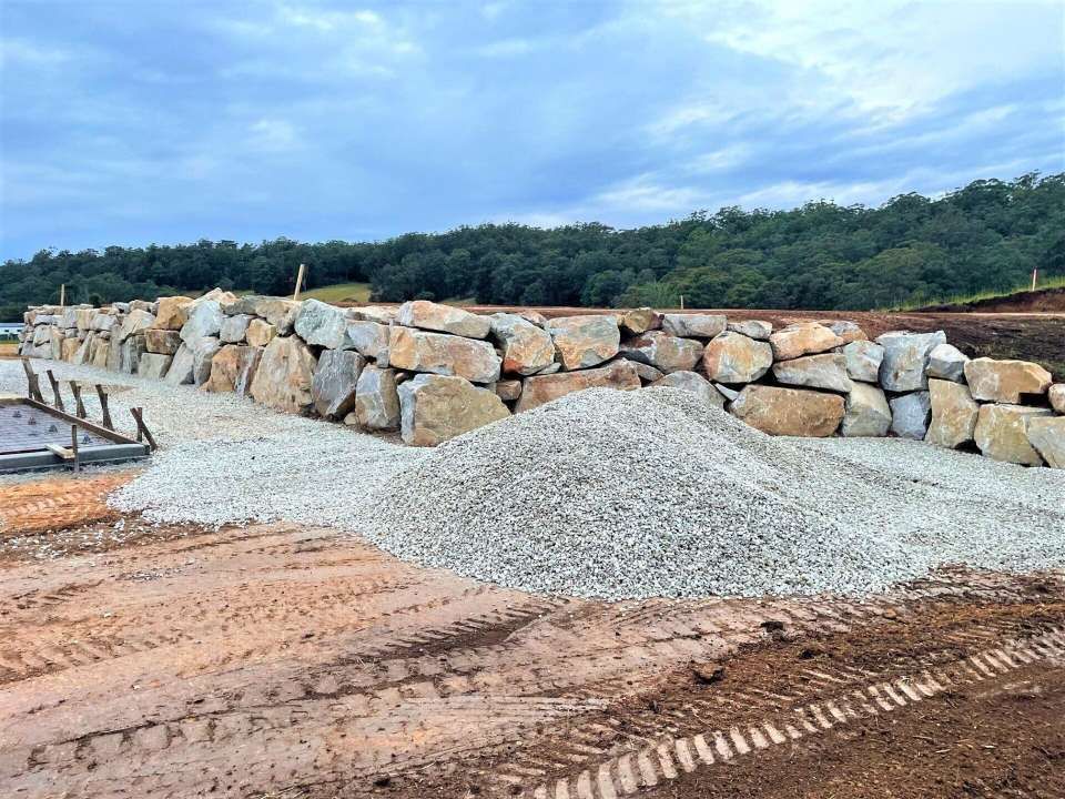 A Pile Of Gravel Is Sitting In Front Of A Stone Wall — Blue Dog Landscape Supplies In Newee Creek, NSW