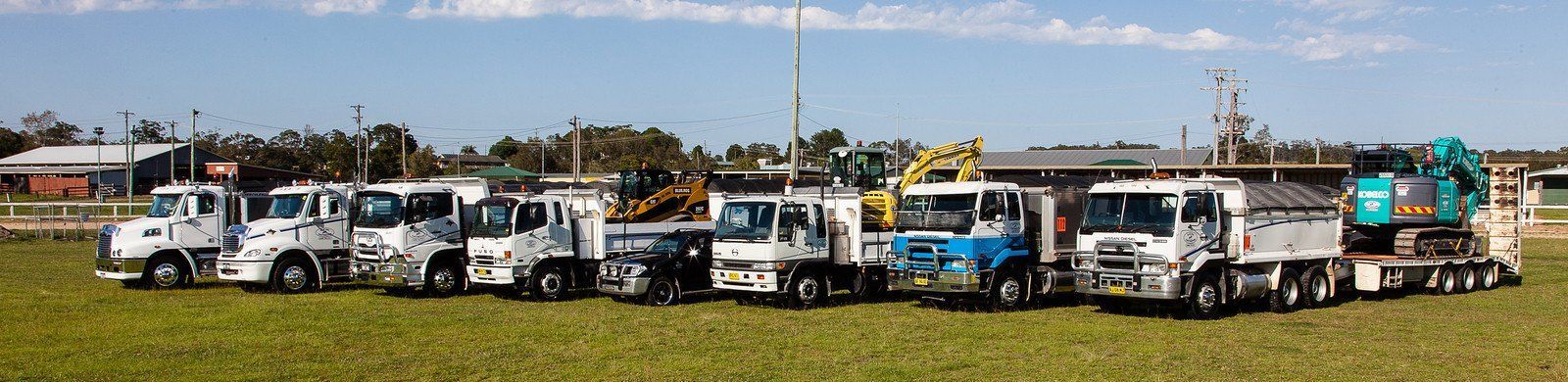 A Row Of Trucks Are Parked In A Grassy Field — Blue Dog Landscape Supplies In Newee Creek, NSW