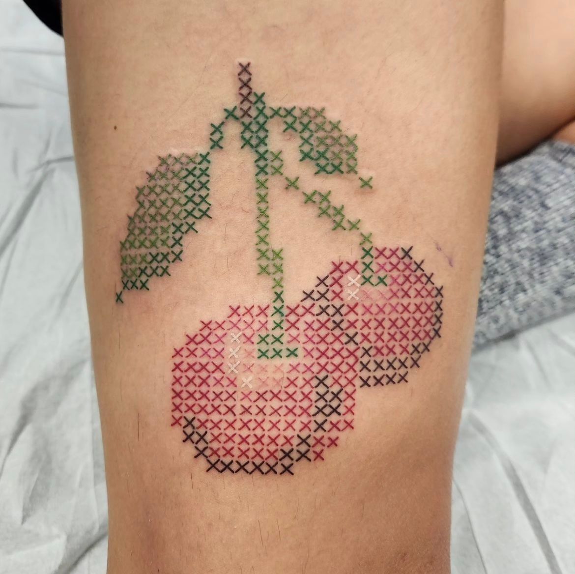 Cross Stitch Cherry Tattoo by Sheila Anderson at Crimson Empire Tattoo in Edmonton Alberta Canada