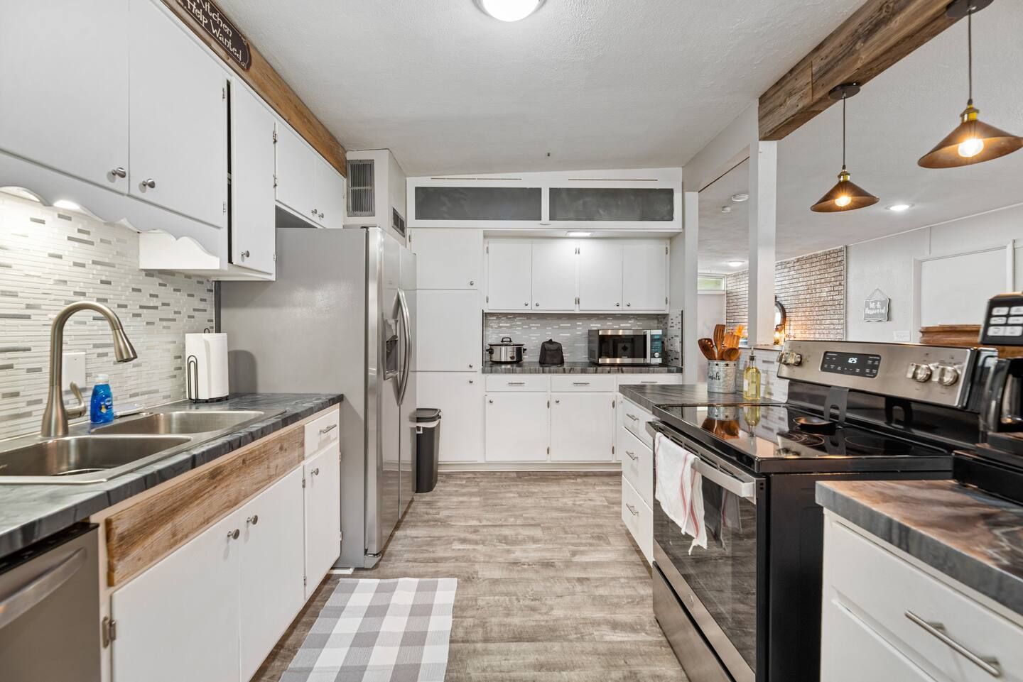 A kitchen with white cabinets , stainless steel appliances , a sink , and a stove.