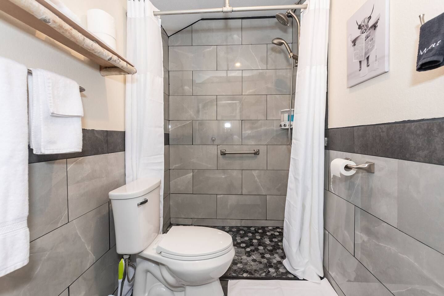 A bathroom with a toilet , shower , and towels.