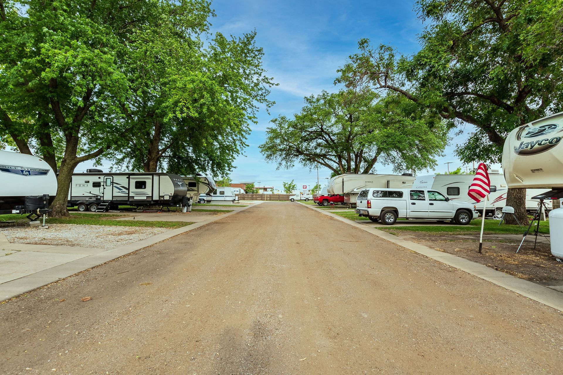 A row of rvs are parked on the side of a dirt road.