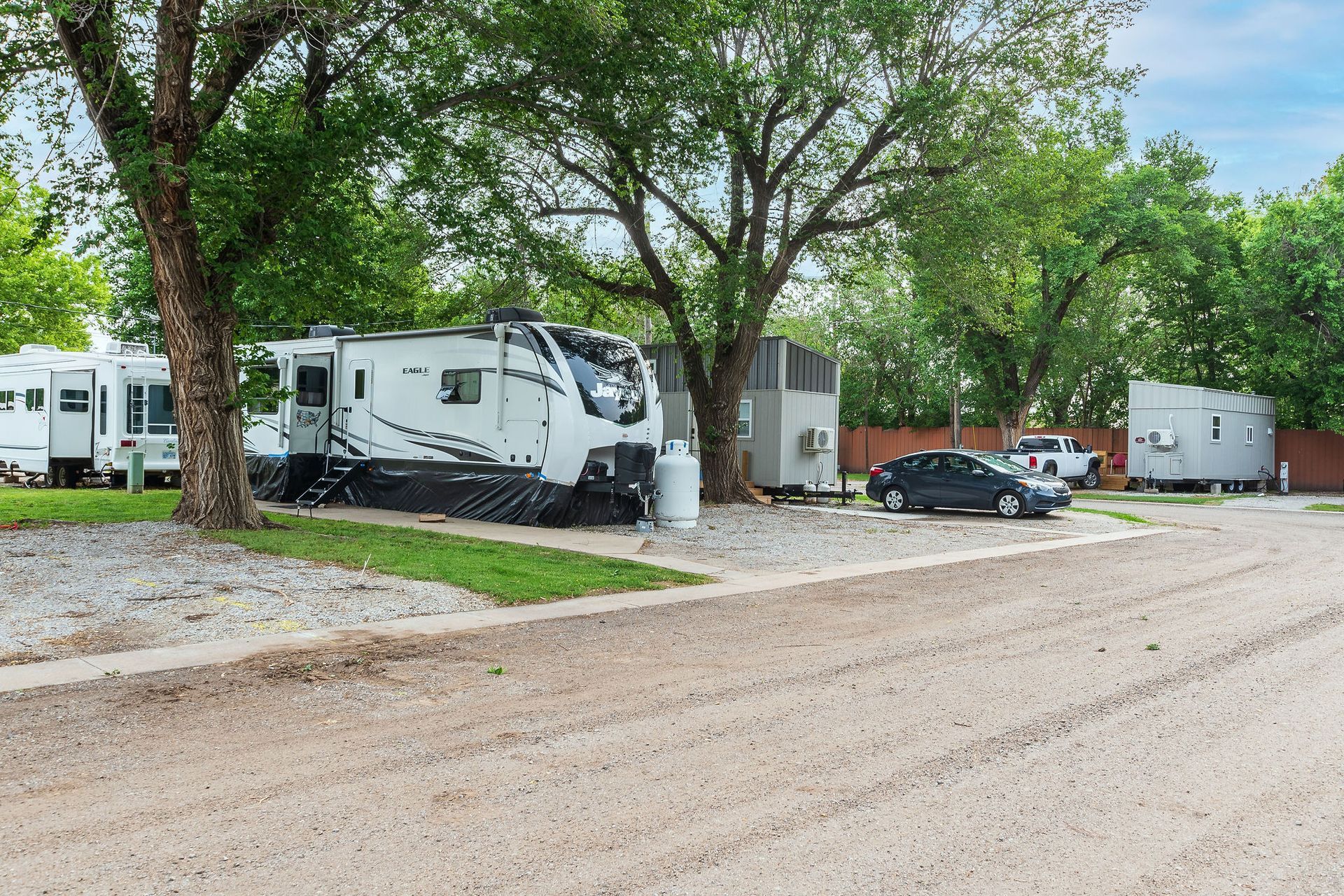 A group of rvs are parked in a gravel lot.