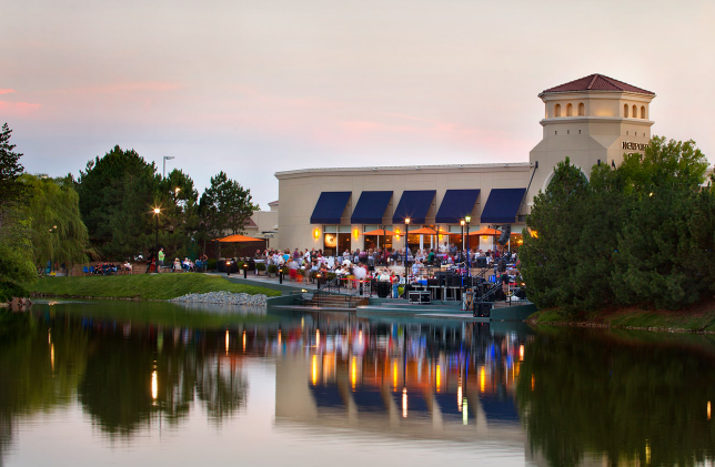 A large building with blue awnings is sitting next to a lake.
