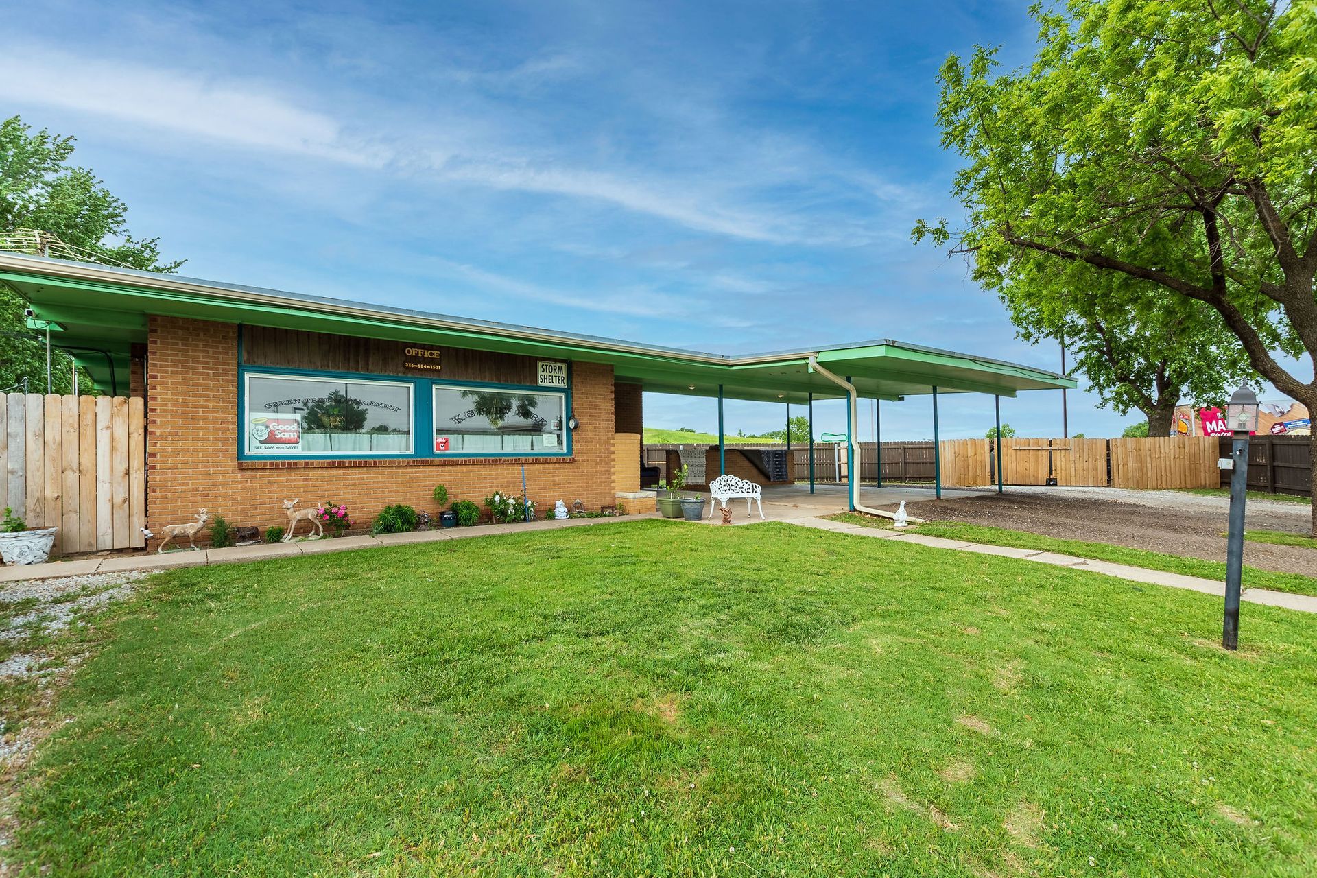 A brick house with a green roof and a large lawn in front of it.