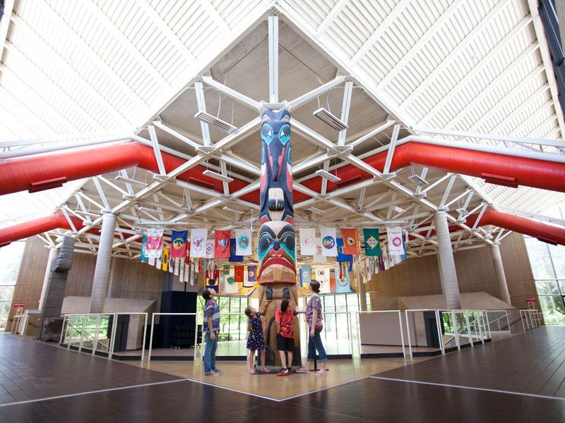 A group of people standing in a building with flags hanging from the ceiling