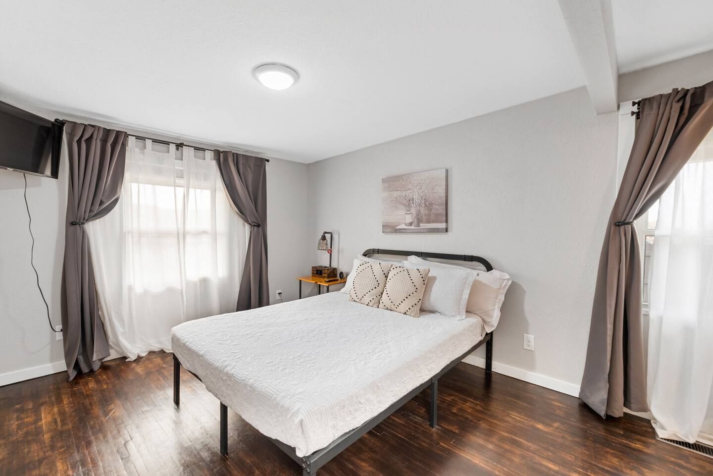 A bedroom with a bed , curtains and a television.