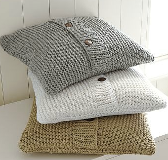 Three knitted pillows are stacked on top of each other on a table.