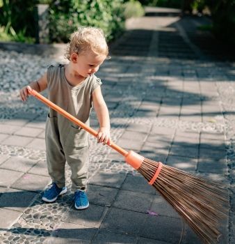 a little boy is holding a broom on a sidewalk .