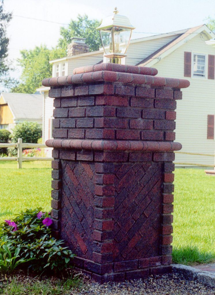 A brick pillar with a bell on top of it