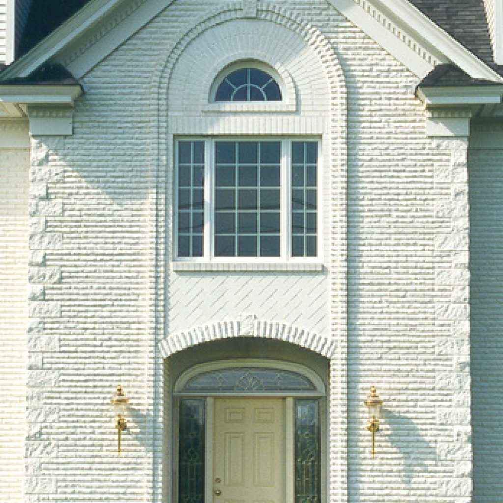 A white brick building with a door and two windows