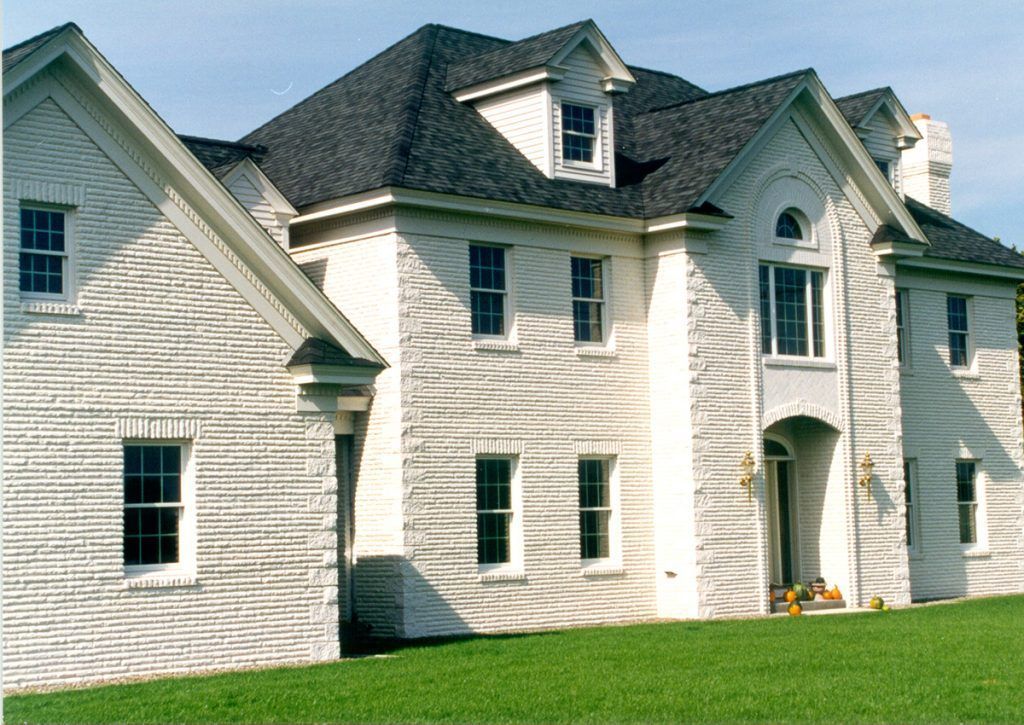 A large white brick house with a black roof
