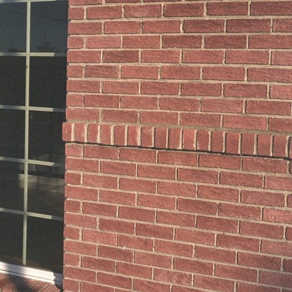 A red brick wall with a window in the background