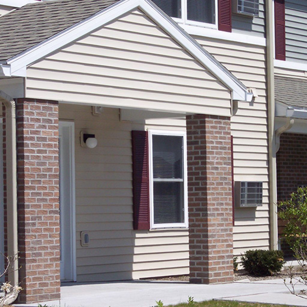 A house with a brick porch and a white siding