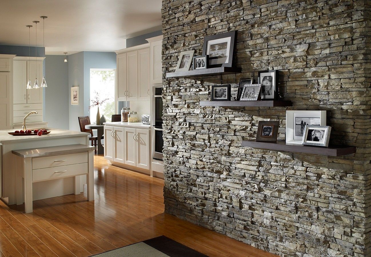 A kitchen with a stone wall and shelves filled with pictures.