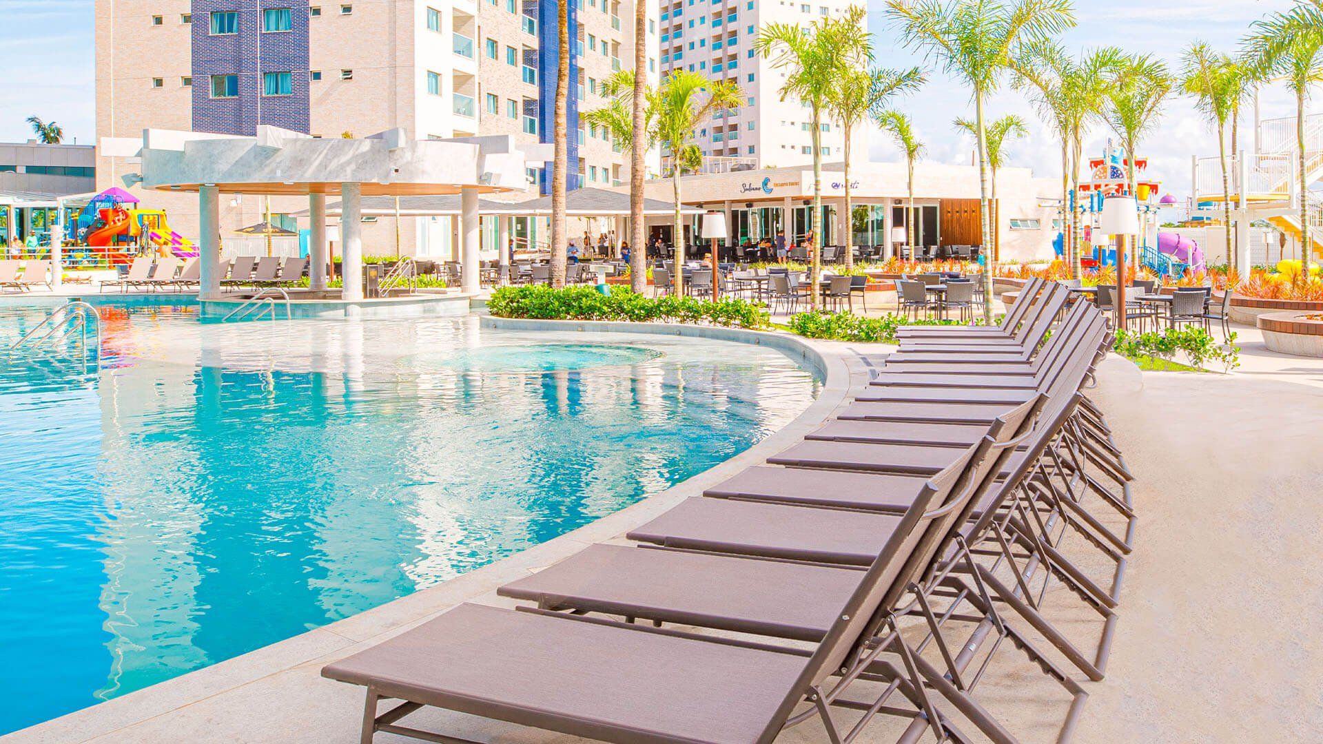 Uma fileira de espreguiçadeiras ao lado de uma grande piscina.