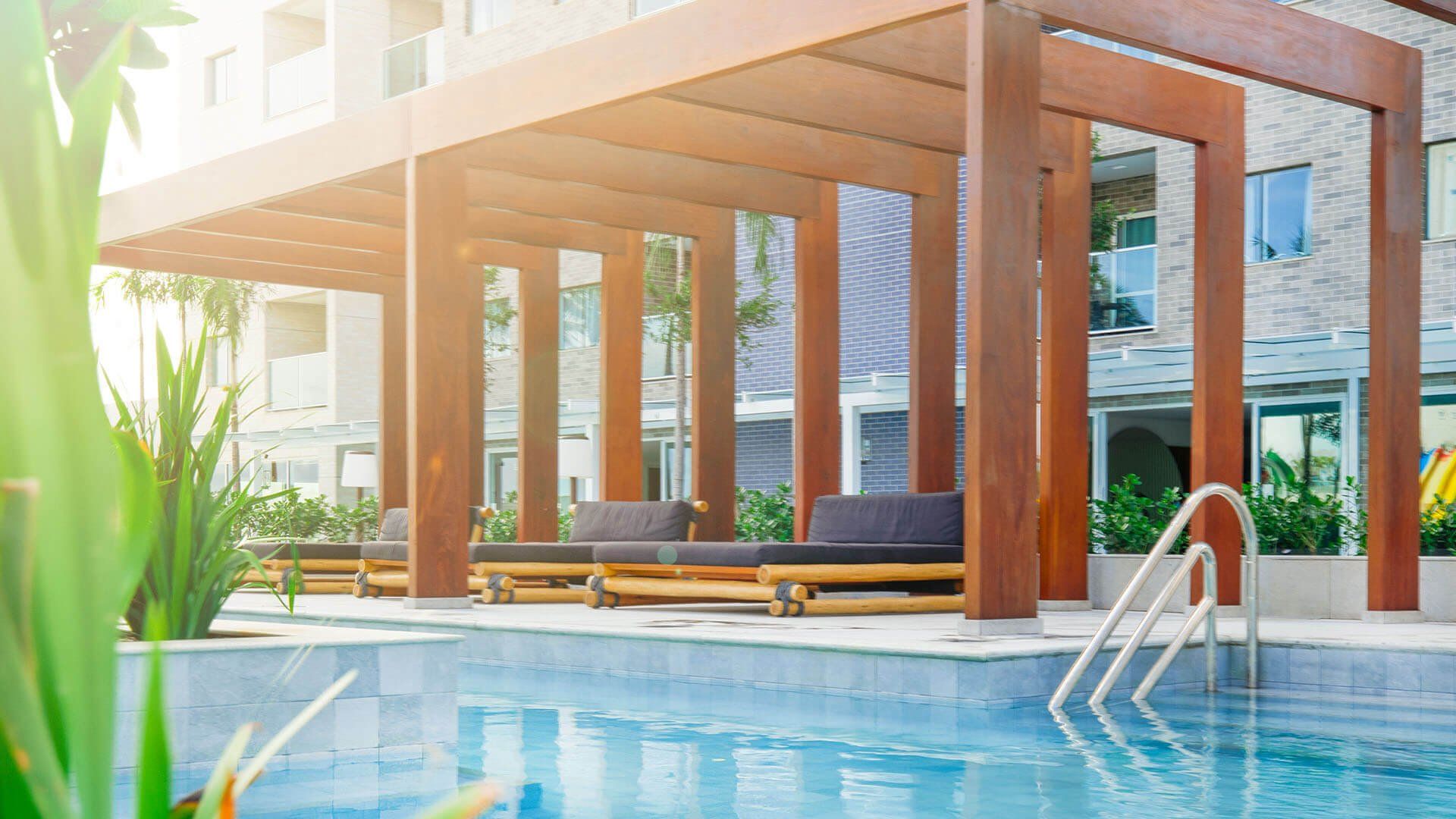 Há uma piscina com uma pérgola de madeira sobre ela.