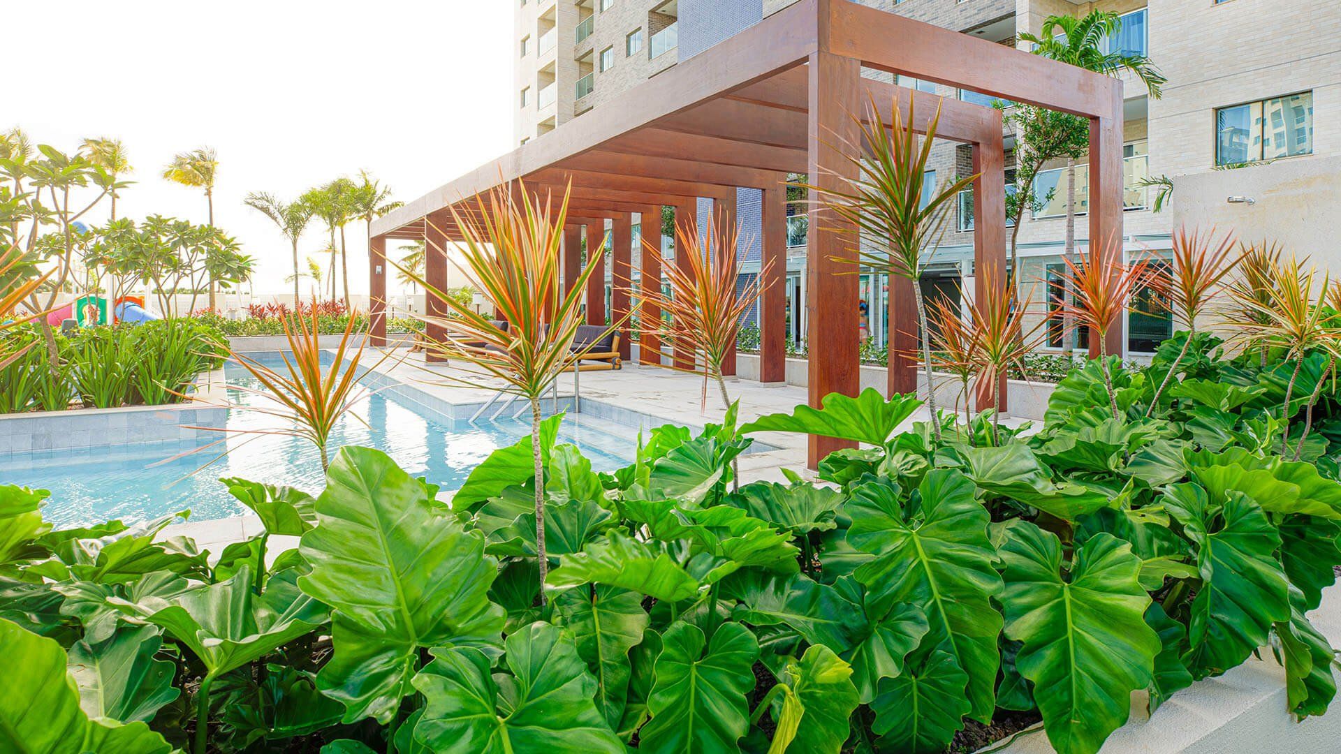 Uma grande piscina cercada por muitas plantas e árvores verdes.