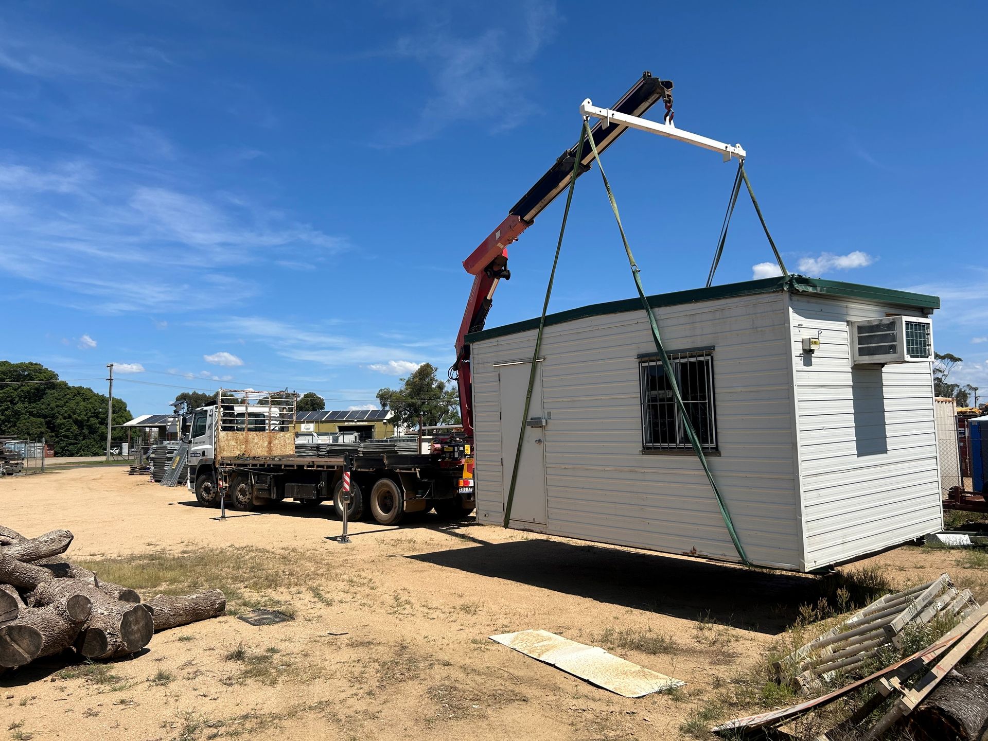 A Blue Truck With A Flatbed Is Parked In A Dirt Lot — Kingaroy Crane Trucks & Equipment Hire In Kingaroy, QLD