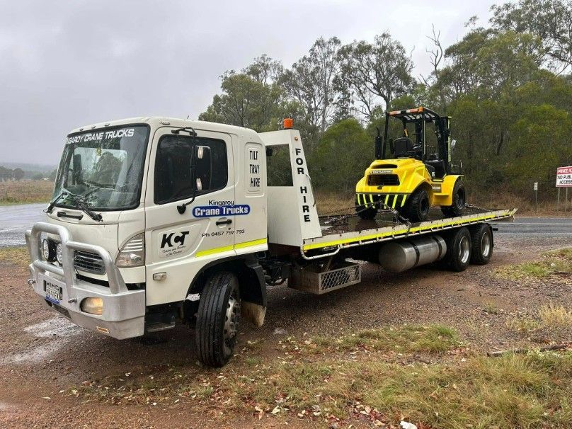A Tow Truck With A Yellow Forklift On The Back Is Parked — Kingaroy Crane Trucks & Equipment Hire In Kingaroy, QLD