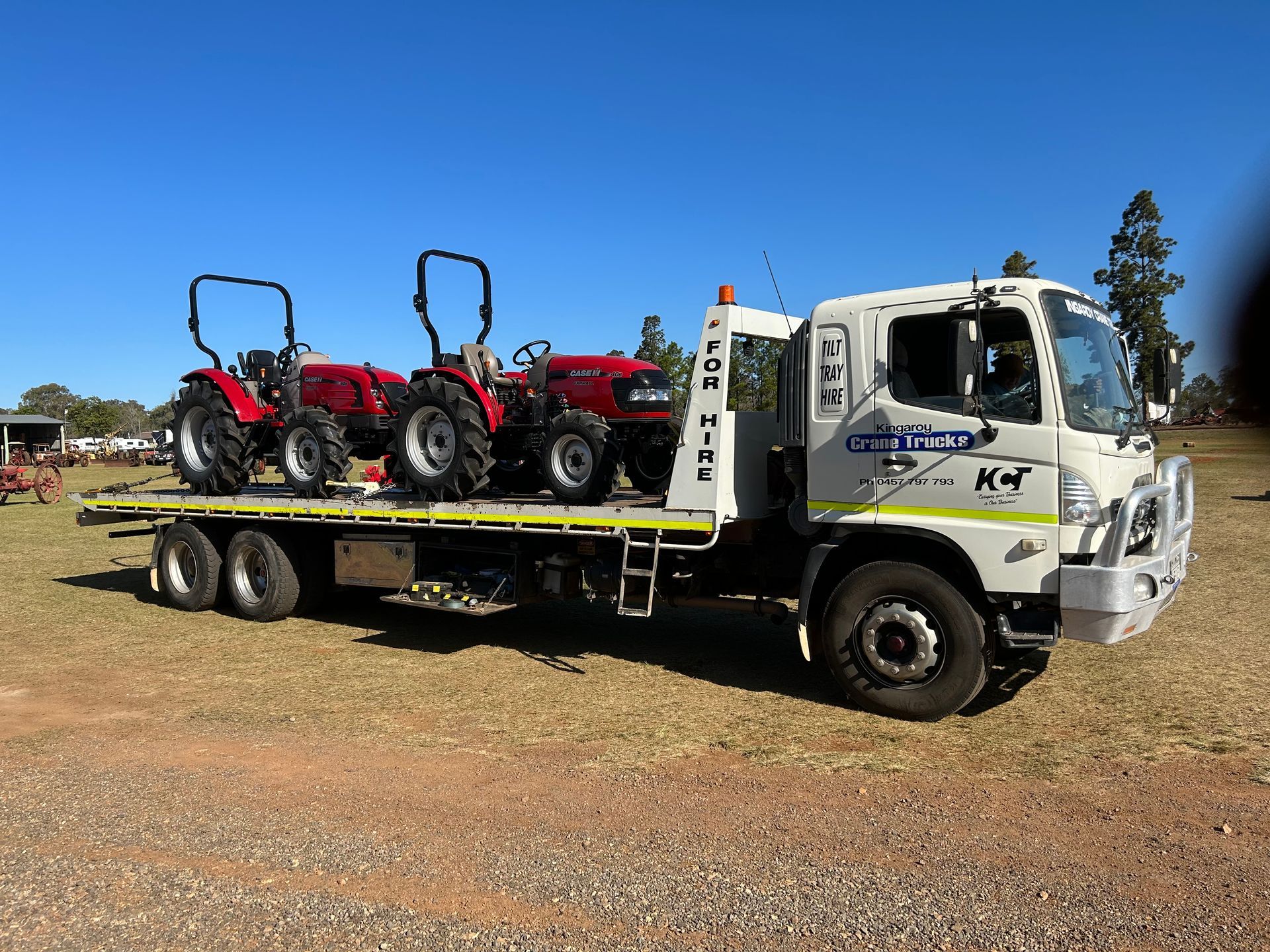 Two Trucks Are Parked Next To Each Other On A Dirt Road — Kingaroy Crane Trucks & Equipment Hire In Kingaroy, QLD