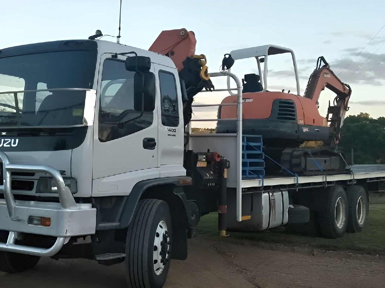 A White Truck With An Excavator On The Back Of It — Kingaroy Crane Trucks & Equipment Hire In Proston, QLD