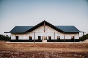 White barn with black accents and a dark blue roof under a clear sky.