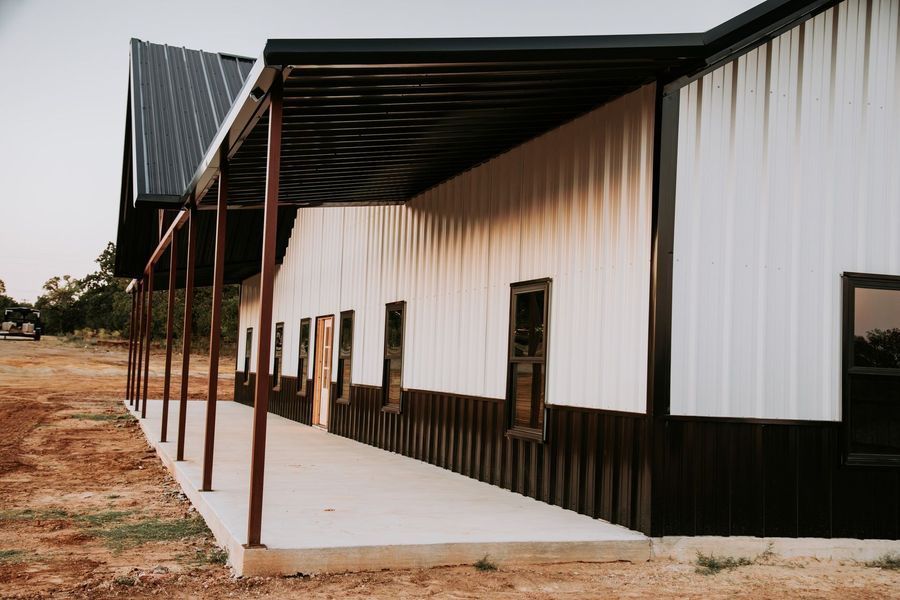 Exterior of a white and black metal building with a covered porch.
