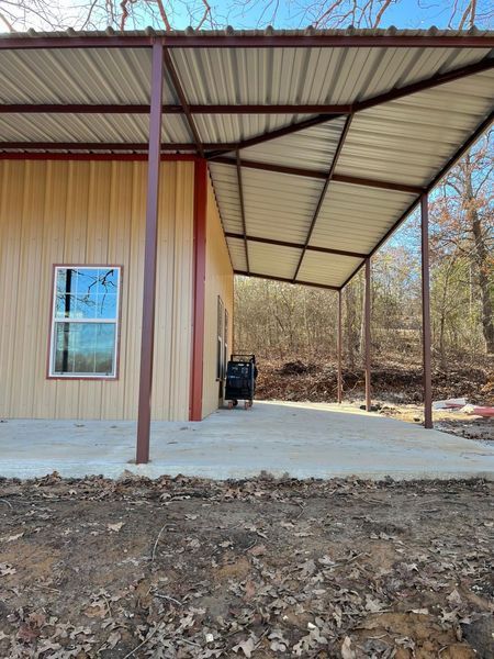 Tan building with brown awning, concrete patio. A window is visible.