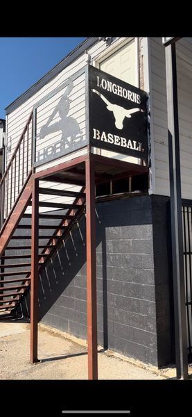 Sign for Longhorn Baseball, with the team logo, and a batter silhouette above a metal staircase.