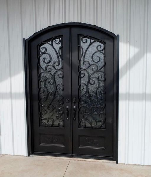 Black, ornate double doors with glass and scrollwork, set in a white building.