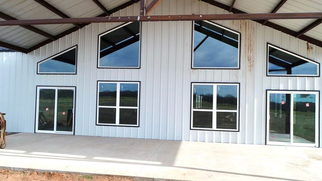 White metal building with large windows and doors, under a brown roof.