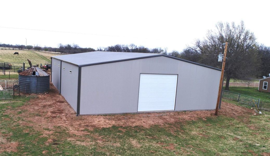 Gray metal shed with white door, on a grassy lot.