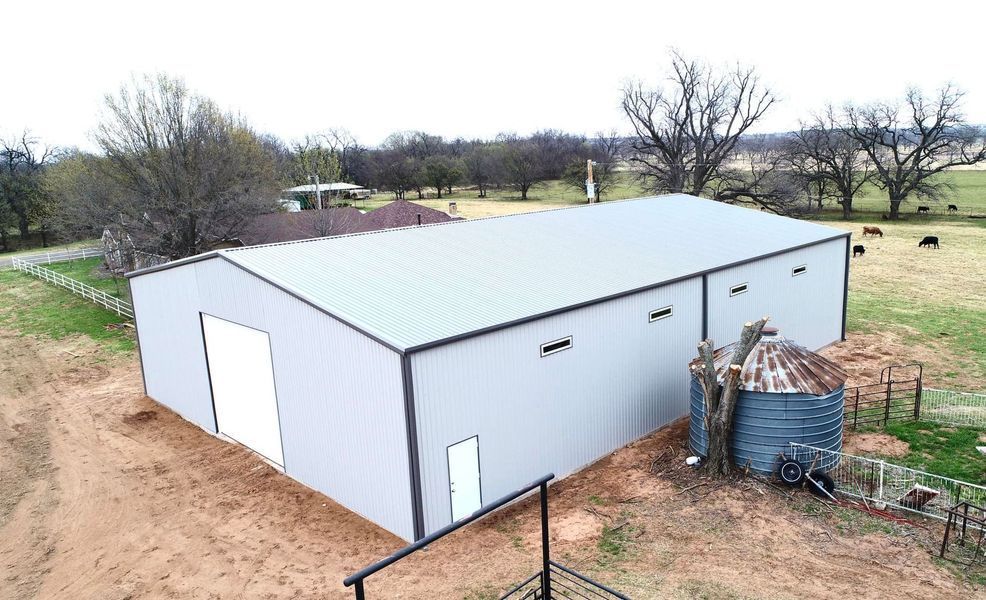 Large metal barn on grassy property with water tank.