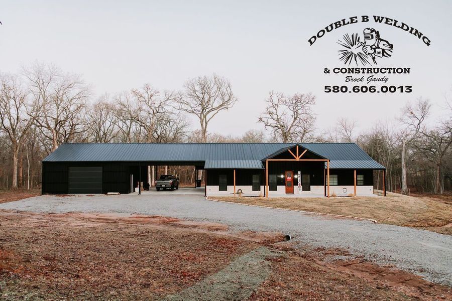 Modern house with a carport, driveway and trees in the background; Double K Welding & Construction sign displayed.