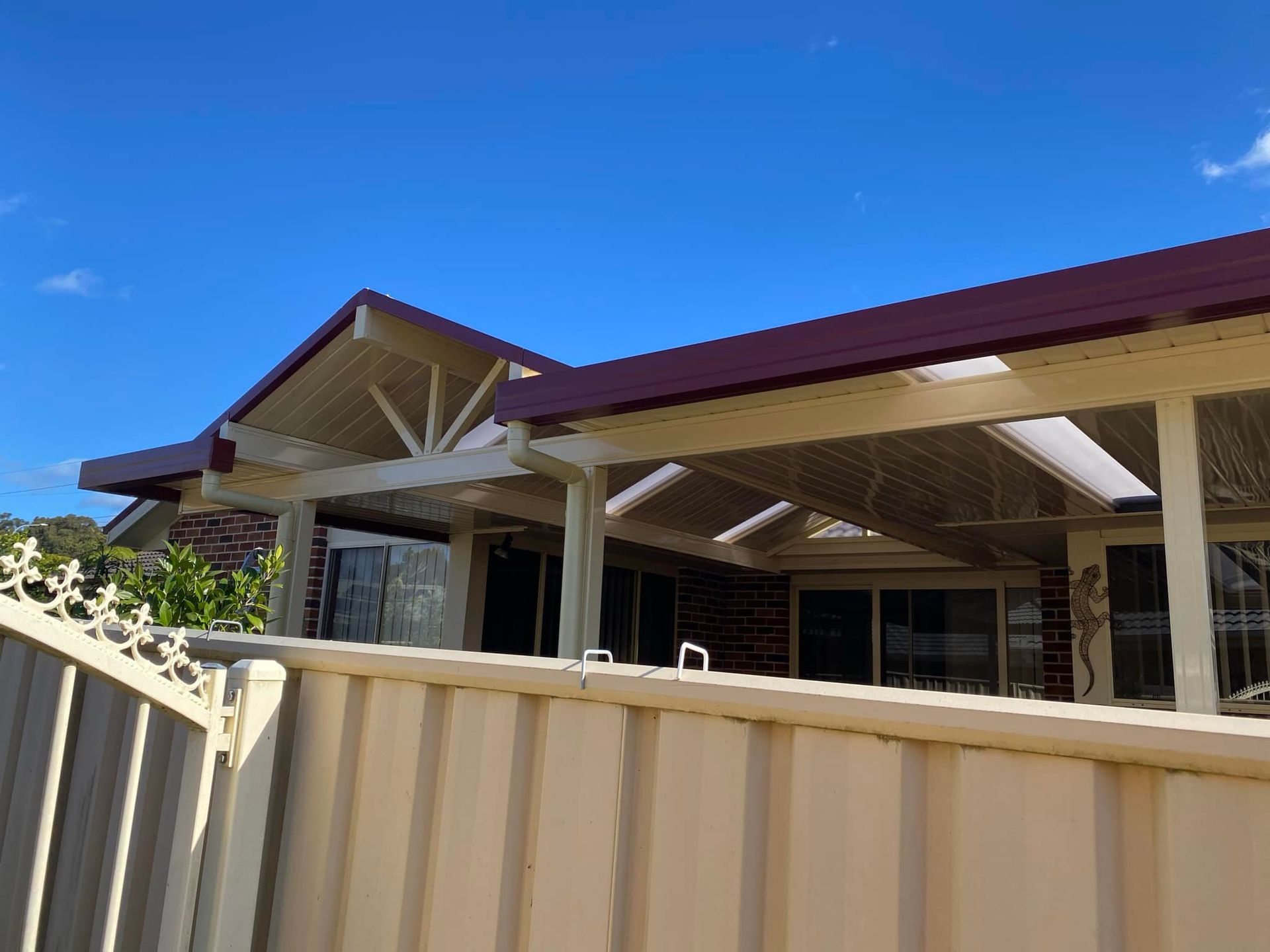 A house with a red roof and a white fence in front of it.
