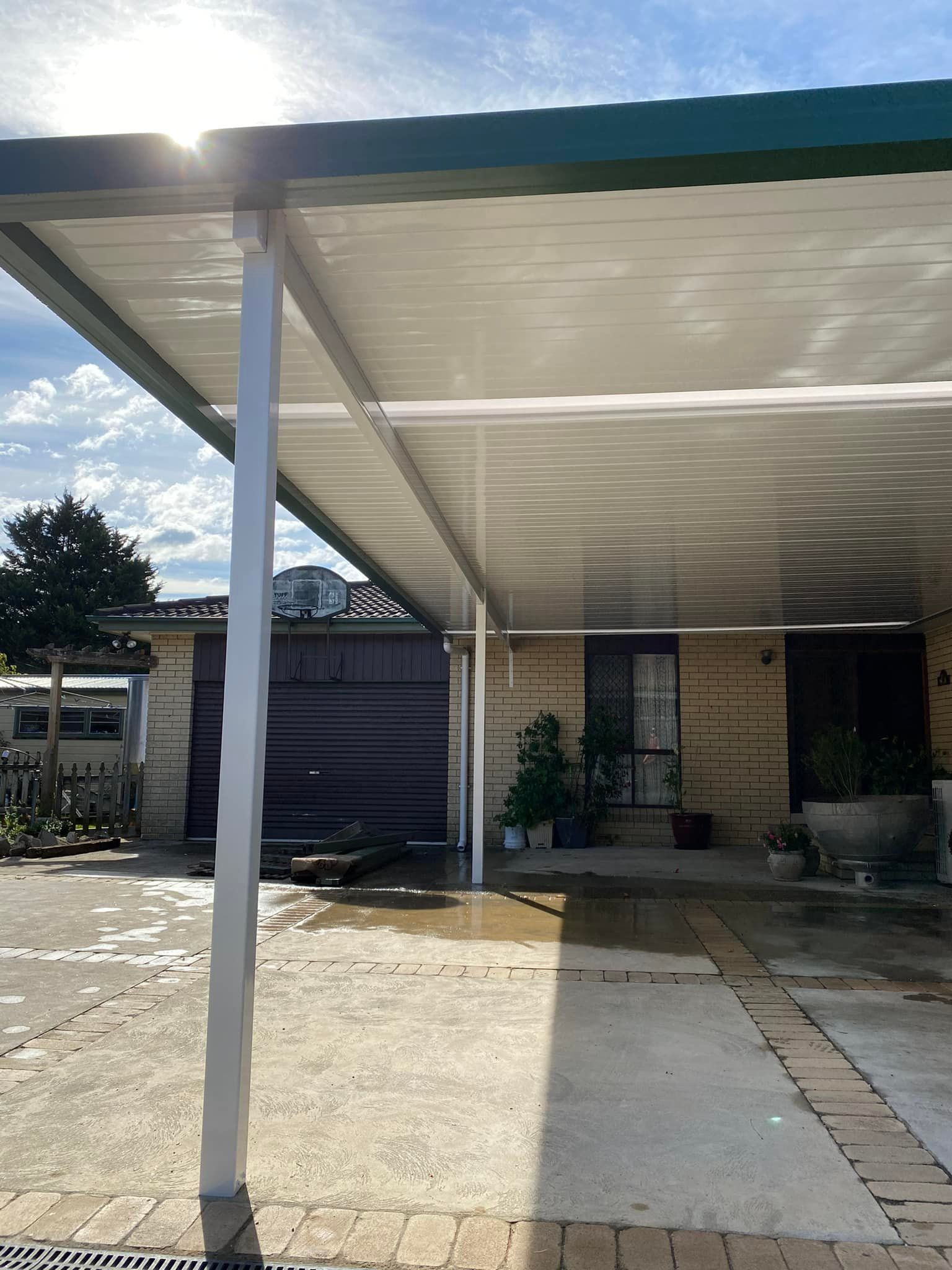 A carport with a canopy over it is in front of a house.