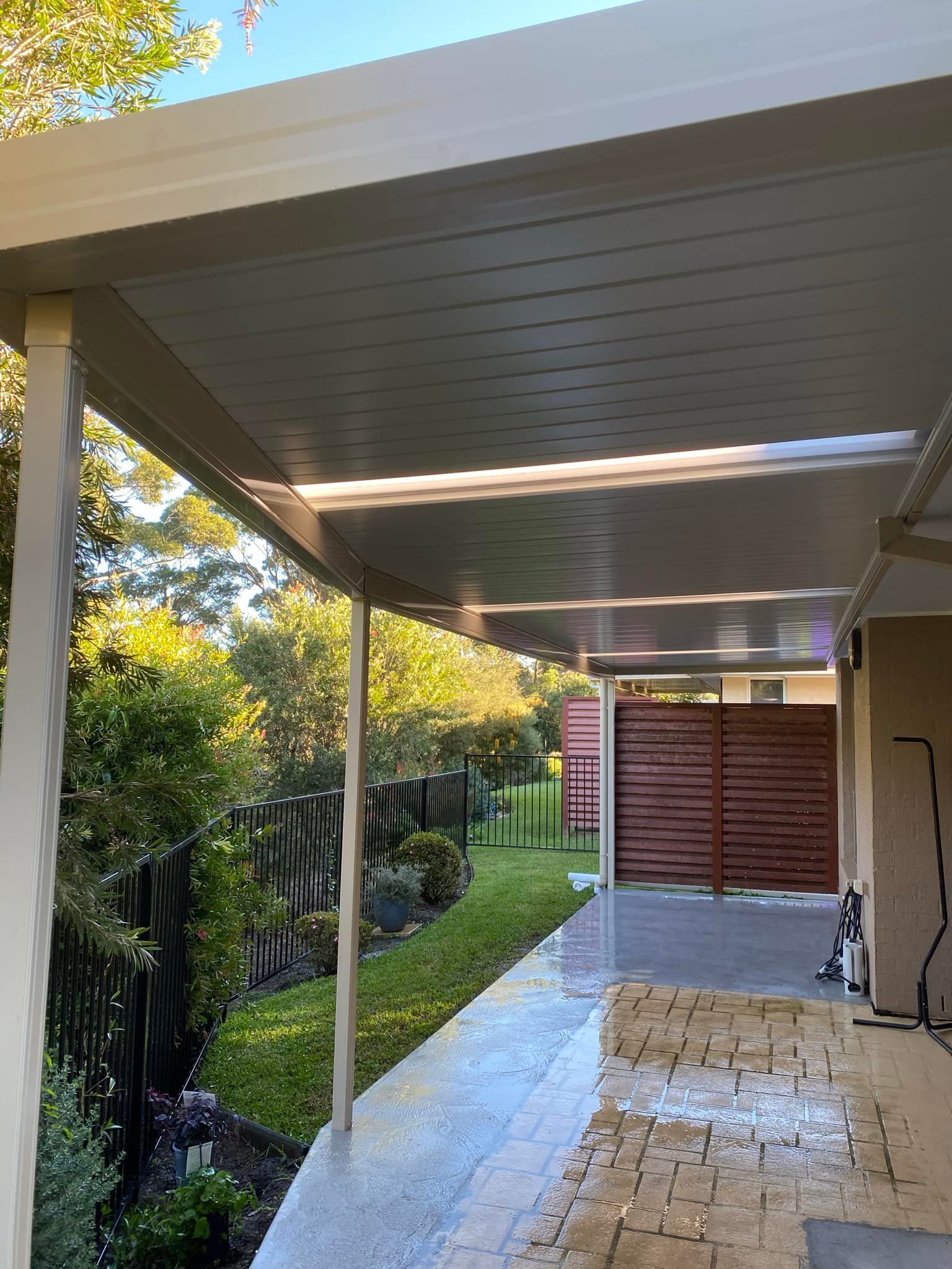 A covered walkway leading to a house with a wooden gate.
