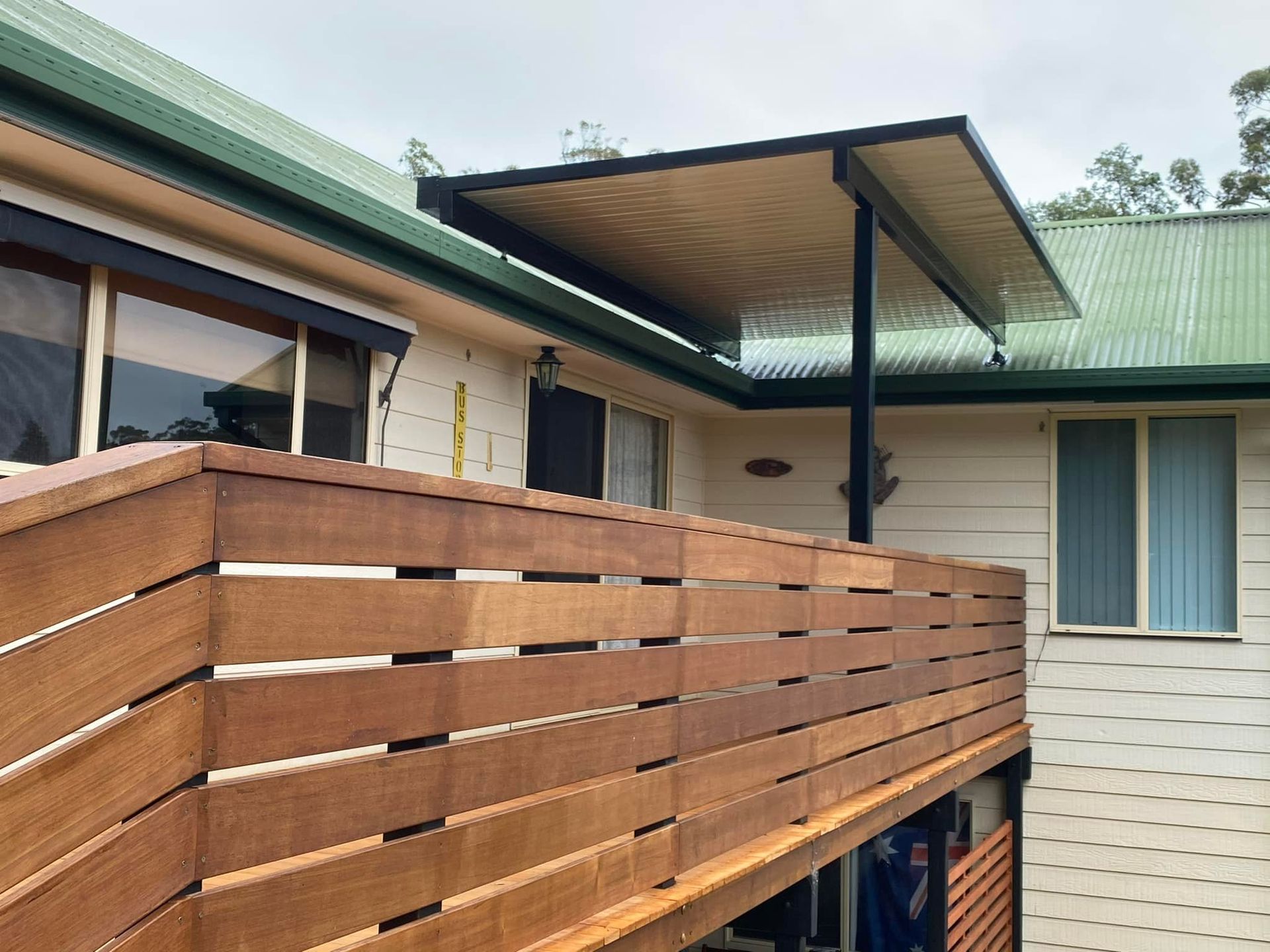A house with a wooden deck and a green roof