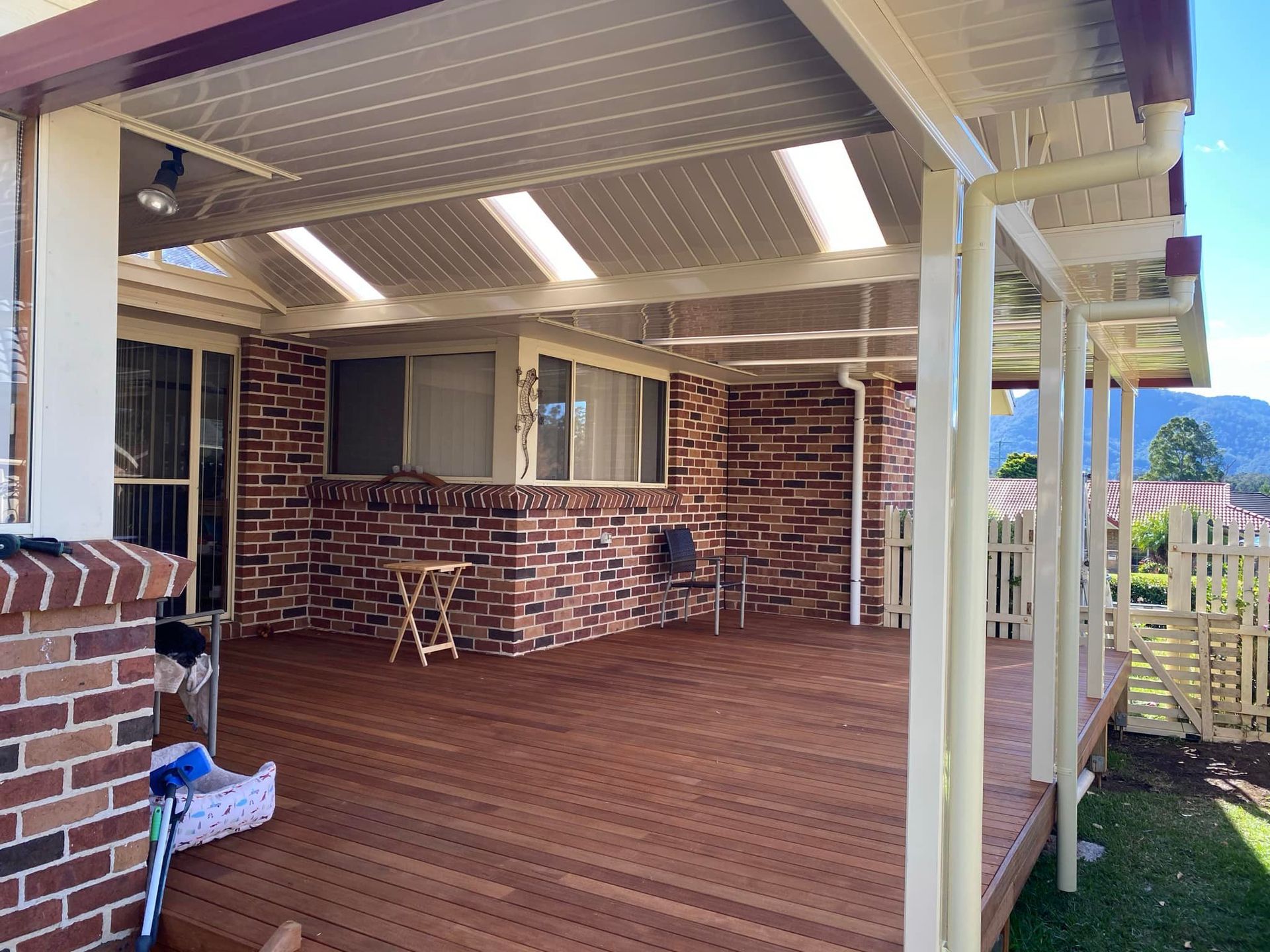 A white patio cover is being installed on the side of a brick house.