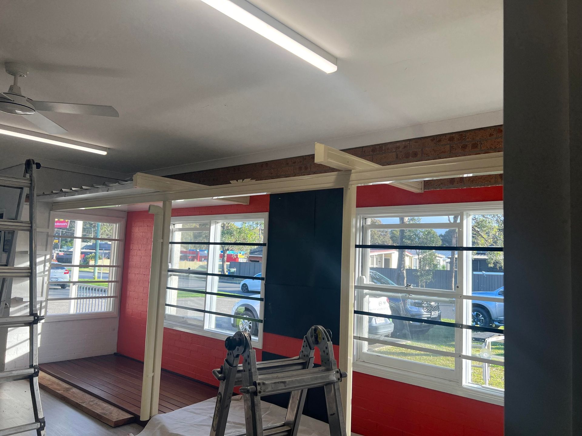 A room with a lot of windows and a ladder in it.