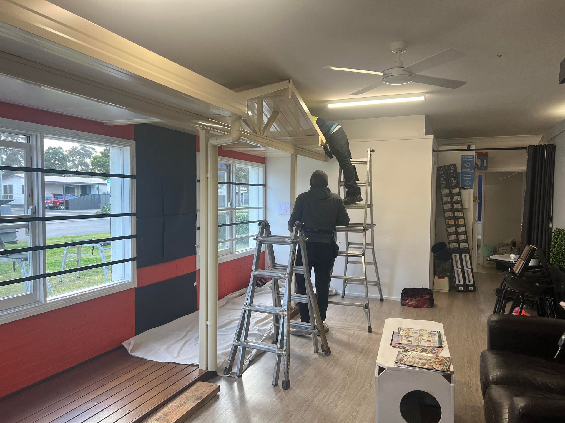 A man is standing on a ladder in a living room.