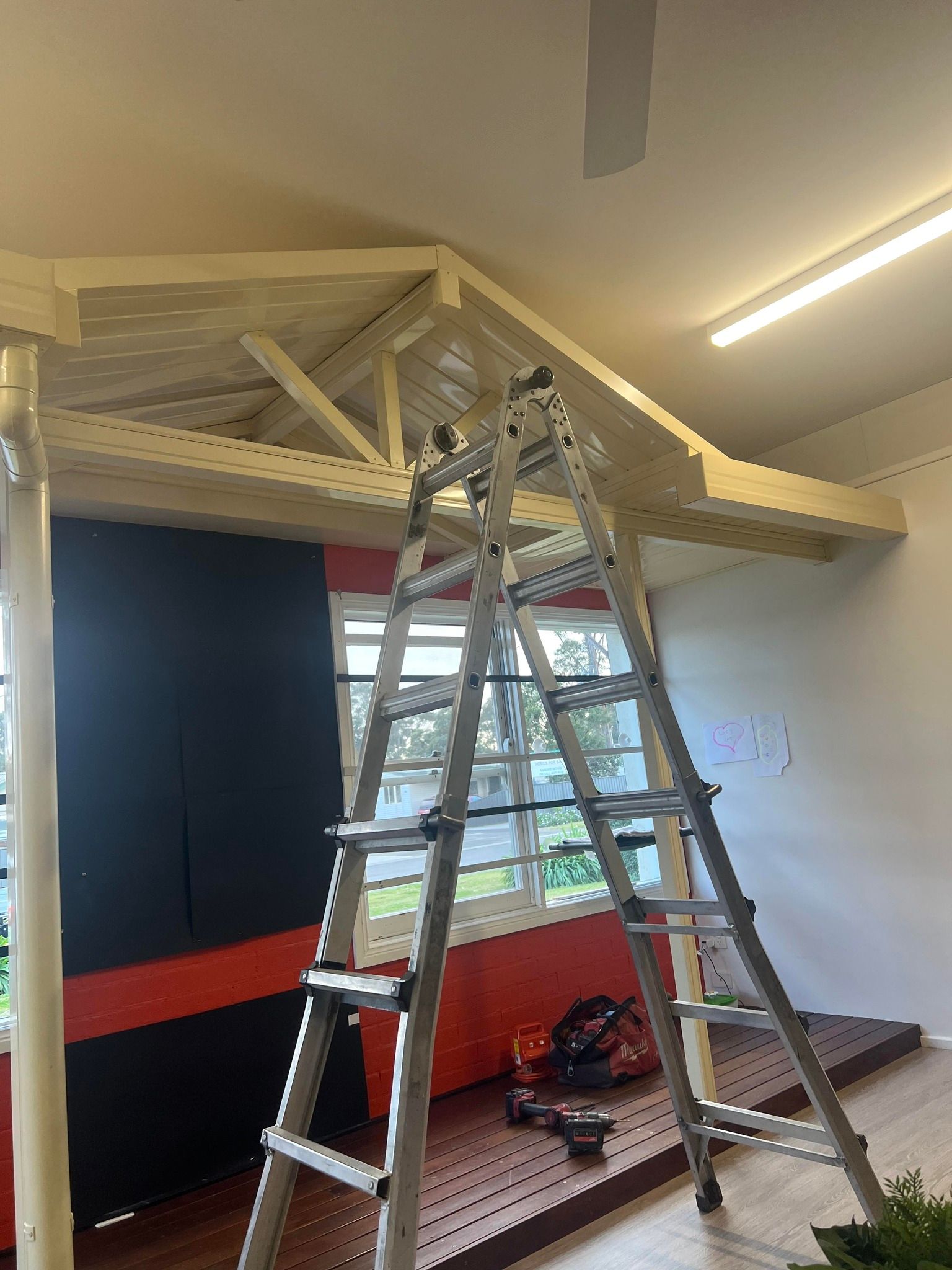 A ladder is sitting on top of a wooden structure in a room.